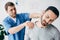 Focus of suffering man and doctor massaging man neck in massage cabinet at clinic
