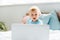 Focus of surprised toddler kid looking at laptop in modern bedroom