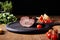 Focus of tasty ham on board near parsley, cherry tomatoes and baguette on wooden table isolated on black