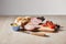 Focus of tasty ham on cutting board with knife, cherry tomatoes, olives and baguette on wooden table isolated on grey