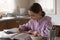 Focused adolescent kid girl studying alone in kitchen.