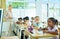 Focused aframerican preteen schoolgirl writing in workbook in class