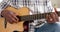 Focused african american senior man playing guitar at home, slow motion