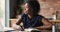 Focused African woman sit at table writing in personal diary