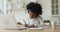 Focused afro american schoolgirl studying remote online from home.