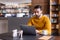 focused arabian freelancer working on laptop near cup of coffee in restaurant, blurred foreground.