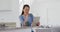 Focused asian woman sitting at table, drinking coffee and using tablet in kitchen