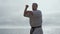 Focused athlete exercising karate on beach closeup. Man training fighting skills