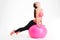 Focused attractive young fitness woman doing stretching on pink fitball