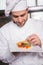 Focused baker putting flower on the pastry with fruit