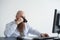 Focused bald man with a red beard drinks coffee and works at the computer. Male manager in a white shirt at a personal