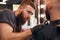 Focused barber shaving beard of man