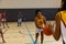Focused biracial female basketball players with male coach playing basketball at gym