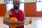 Focused biracial male coach holding basketball and using tablet at gym