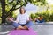 Focused biracial senior woman practising yoga with friends in sunny garden, copy space