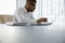 Focused Black millennial businessman typing on laptop in modern office