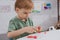 focused boy with colorful plasticine sculpturing figure at table