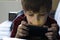 Focused boy enthusiastically plays in a smartphone.