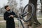 Focused businessman repairing bicycle in park, showing multitasking and problem-solving