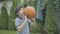 Focused Caucasian brunette boy throwing ball and making victory gesture. Portrait of happy cute kid rejoicing outdoors