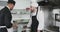 Focused caucasian male chef instructing trainee male chef in kitchen, slow motion