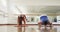 Focused caucasian male instructor and female student practicing yoga in gym, slow motion