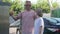 Focused Caucasian man paying for car wash with smartphone outdoors standing with son at black vehicle. Concentrated