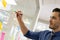 Focused caucasian man working and writing on glass board in office