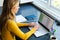 Focused caucasian woman sitting at desk, working from home and using laptop in sunny room