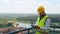 Focused Caucasian young man in uniform and helmet working on digital tablet while standing on construction site