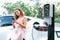 Focused charging station recharging EV car on blurred background. Synchronos