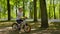 Focused child boy is riding a bike in city park in slow motion among trees.