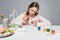 Focused child painting easter eggs at table