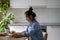 Focused concentrated young Asian female freelance blogger working on laptop in kitchen