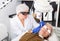 Focused cosmetologist performing laser resurfacing to senior woman