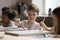 Focused cute kid drawing on class in group of classmates