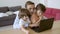 Focused dad hugging sons, using laptop and talking
