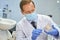 Focused dental technician in mask holding a model of teeth