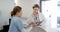 Focused diverse female doctors using tablet and discussing over hospital reception desk, slow motion