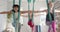 Focused diverse fitness teenage girls exercising in aerial yoga class in big white room, slow motion