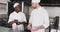 Focused diverse male chef instructing trainee male chef in kitchen, slow motion