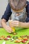 Focused face of a boy with glasses, who decorates a heart-shaped cake with the help of icing in a tube.