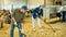 Focused farmer cleaning hay bedding in goat shed