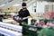 Focused female worker wearing protective face mask working at fruit warehouse carrying box with mangos