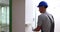 Focused foreman in helmet paints white walls with roller