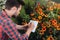 Focused gardener making notes in notebook while checking plants in garden