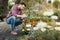 Focused gardener making notes in notebook while checking plants in garden