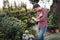 Focused gardener making notes in notebook while checking plants in garden