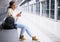 Focused girl is sitting on a subway station bench with a mobile phone