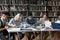 Focused group of happy diverse students studying in library.